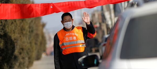 A village committee member wearing face mask and vest, stops a car for checking as he guards at the entrance of a community to prevent outsiders from entering - Sputnik International