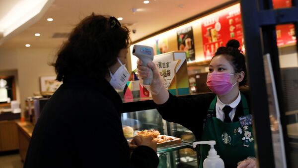 A worker uses a thermometer to check the temperature of a customer as she enters a Starbucks shop as the country is hit by an outbreak of the new coronavirus, in Beijing, China January 30, 2020 - Sputnik International