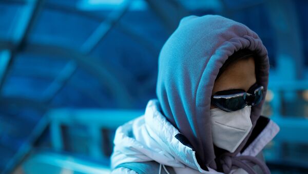 A woman wearing a face mask and goggles uses an escalator near Beijing Railway Station - Sputnik International