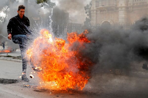 A Palestinian demonstrator kicks a burning tire during a protest against the U.S. president Donald Trump’s Middle East peace plan, in Bethlehem in the Israeli-occupied West Bank January 29, 2020. - Sputnik International