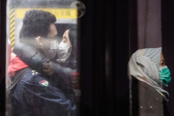 A couple wearing face masks kiss on an underground metro train as another passenger (R) is reflected on a platform glass door during a Lunar New Year of the Rat public holiday in Hong Kong on January 27, 2020, as a preventative measure following a coronavirus outbreak which began in the Chinese city of Wuhan.  - Sputnik International