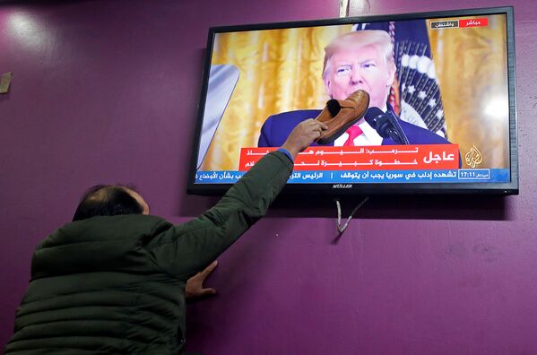 A Palestinian man places a shoe on a television screen broadcasting the announcement of Mideast peace plan by U.S. President Donald Trump, in a coffee shop in Hebron in the Israeli-occupied West Bank January 28, 2020.  - Sputnik International