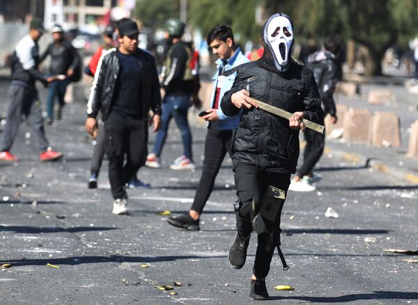An Iraqi protester wearing a mask runs amid clashes with security forces at an anti-government demonstration in Al-Khillani square in the capital Baghdad, on January 27, 2020. - Sputnik International
