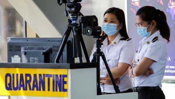 Airport personnel monitor a thermal scanner as passengers arrive at the Ninoy Aquino International Airport in Pasay, Philippines - Sputnik International