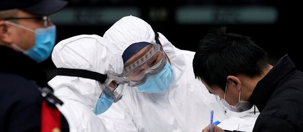Staff members wearing protective masks check a passenger at Shanghai railway station in Shanghai, China, as the country is hit by an outbreak of a new coronavirus, February 2, 2020. - Sputnik International