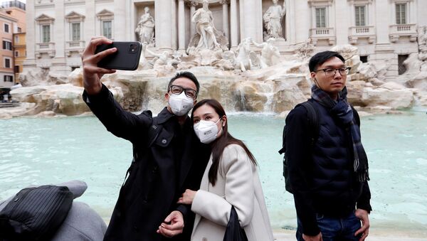 Tourists wearing protective masks take a selfie in front of the Trevi's Fountain after two cases of coronavirus were confirmed in the country, in Rome, Italy - Sputnik International