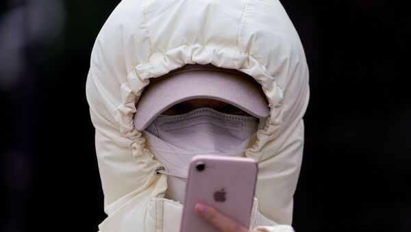 A woman wearing a mask checks her mobile phone in Shanghai, China January 29, 2020 - Sputnik International