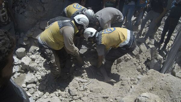 This photo provided by the Syrian Civil Defense White Helmets, which has been authenticated based on its contents and other AP reporting, shows Syrian White Helmet civil defense workers pull out a victim from under the rubble of a destroyed building that hit by a Syrian government airstrike, in the northern town of Ariha, in Idlib province, Syria, Friday, July 12, 2019 - Sputnik International