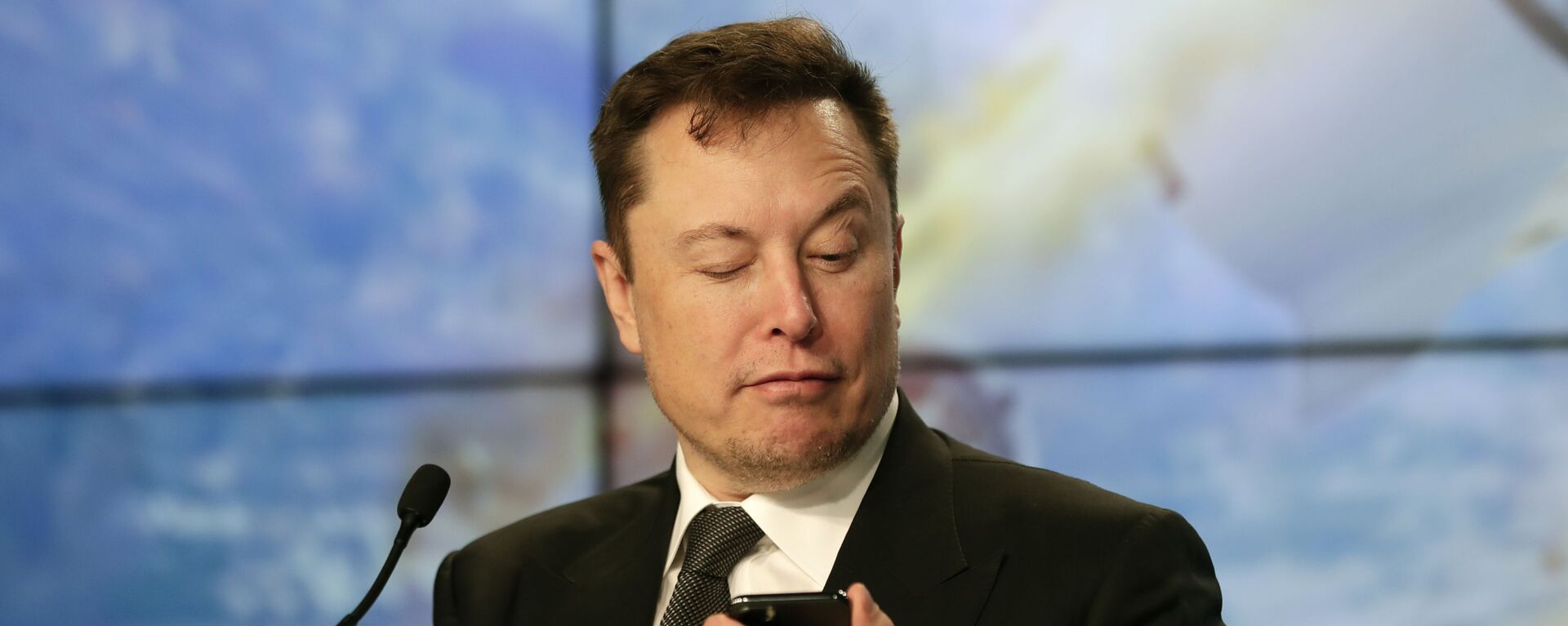 Elon Musk founder, CEO, and chief engineer/designer of SpaceX jokes with reporters as he pretends to be searching for an answer to a question on a cell phone during a news conference after a Falcon 9 SpaceX rocket test flight to demonstrate the capsule's emergency escape system at the Kennedy Space Center in Cape Canaveral, Fla., Sunday, Jan. 19, 2020. - Sputnik International, 1920, 21.07.2020