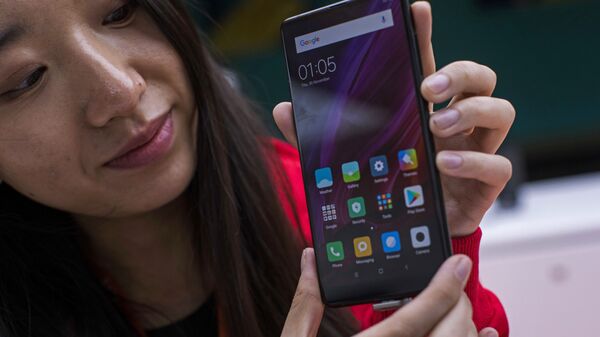 In this Feb. 26, 2018 file photo, a woman shows the new Xiaomi Mi MIX 2 during the Mobile World Congress wireless show, in Barcelona, Spain. - Sputnik International