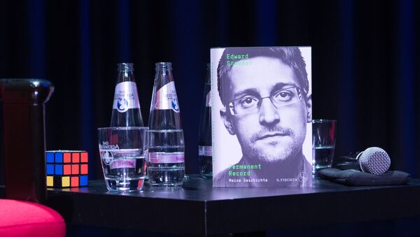 A copy of the book titled Permanent Record by US former CIA employee and whistleblower Edward Snowden is seen next to a Rubik's cube during a video conference on September 17, 2019 in Berlin. - In his book, Snowden tells among others that he used a Rubik's cube to smuggle secret data out of the rooms of the US intelligence service National Security Agency (NSA) - Sputnik International