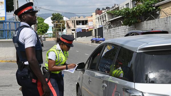 Jamaican police officers check a motorist's details  - Sputnik International
