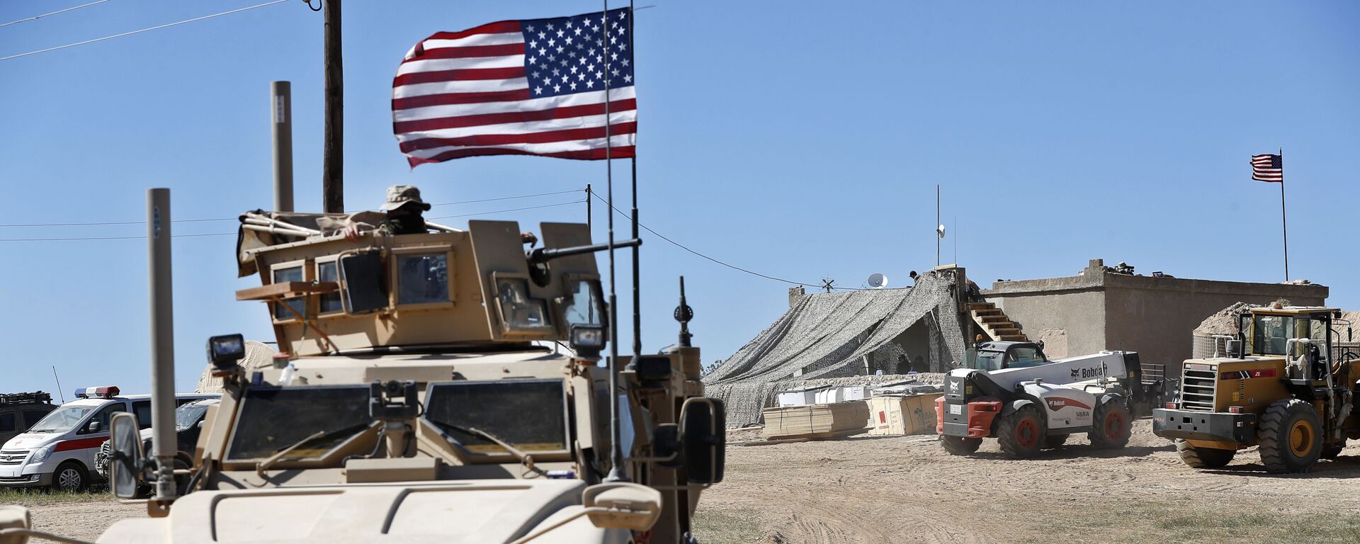 A U.S. soldier, left, sits on an armored vehicle behind a sand barrier at a newly installed position near the tense front line between the U.S-backed Syrian Manbij Military Council and the Turkish-backed fighters, in Manbij, north Syria, Wednesday, April 4, 2018.  - Sputnik International, 1920, 14.06.2023