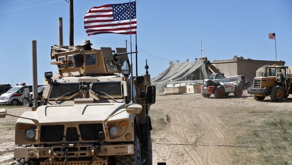 A U.S. soldier, left, sits on an armored vehicle behind a sand barrier at a newly installed position near the tense front line between the U.S-backed Syrian Manbij Military Council and the Turkish-backed fighters, in Manbij, north Syria, Wednesday, April 4, 2018.  - Sputnik International