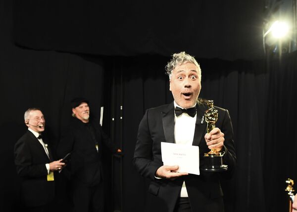 In this photo provided by A.M.P.A.S., Best Adapted Screenplay winner Taika Waititi walks backstage during the 92nd Oscars at the Dolby Theatre in Hollywood, California on 9 February 2020.  - Sputnik International