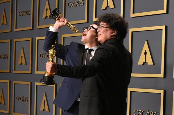 Parasite writers Han Jin-won (L) and Bong Joon-ho pose in the press room with the Oscars for Parasite during the 92nd Oscars at the Dolby Theatre in Hollywood, California on 9 February 2020. Bong Joon-ho won for Best Director, Best Movie, Best Foreign Film and Best Original Screenplay for Parasite.  - Sputnik International