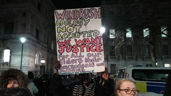 Man holds placard outside Number 10 in crowd demanding justice for Windrush generation 10 Feb 2020 - Sputnik International