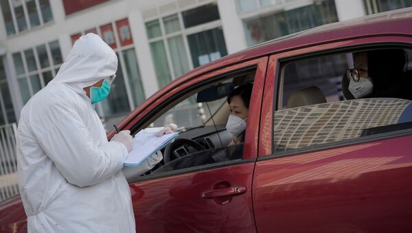 A worker in protective suit gathers information from passengers at an entrance to the car park of a commercial complex after the extended Lunar New Year holiday caused by the novel coronavirus outbreak, in Beijing's central business district - Sputnik International