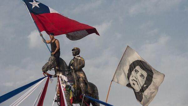 A demonstrator waves a Chilean national flag next to another flag depicting late Chilean musician Victor Jara during a protest against President Sebastian Pinera's government, in Santiago, on January 17, 2020 - Sputnik International