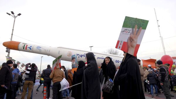 People gather around a model of a satellite-carrier rocket displayed during a ceremony  marking the 37th anniversary of the Islamic Revolution, in Tehran February 11, 2016 - Sputnik International