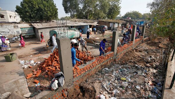 Construction workers build a wall along a slum area as part of a beautification drive along a route that U.S. President Donald Trump and India's Prime Minister Narendra Modi will be taking during Trump's visit later this month, in Ahmedabad, India, February 13, 2020 - Sputnik International