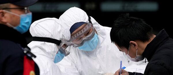 Staff members wearing protective masks check a passenger at Shanghai railway station in Shanghai, China, as the country is hit by an outbreak of a new coronavirus, February 2, 2020. - Sputnik International