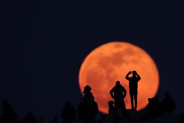 People observe a rising full snow moon as they visit the Areios Pagos hill at the archaeological site of the Acropolis in Athens, Greece, February 9, 2020.  - Sputnik International
