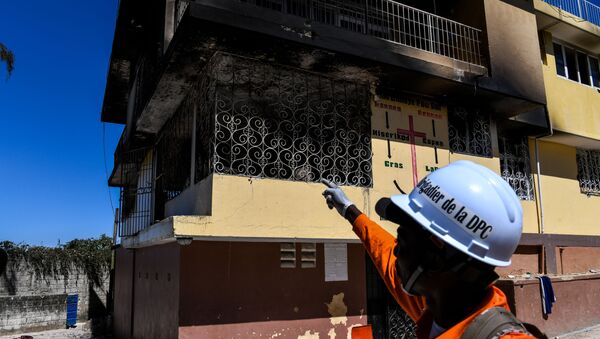 A firefighter points at the Orphanage of the Church of Bible Understanding where a fire broke out the previous night in the Kenscoff area outside of Port-au-Prince February 14, 2020. - Sputnik International