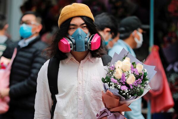 A man wears a gas mask as he holds a bouquet of flowers, following the outbreak of the novel coronavirus on Valentine’s Day in Hong Kong, China February 14, 2020.  - Sputnik International
