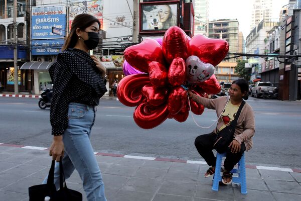 A woman wearing a protective mask walks past a woman selling balloons to celebrate Valentine's Day in Bangkok, Thailand February 13, 2020.  - Sputnik International