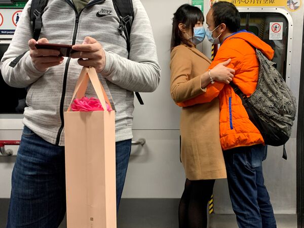 A couple wearing masks embrace in an MTR train, following the outbreak of the novel coronavirus on Valentine's Day in Hong Kong, China February 14, 2020. - Sputnik International