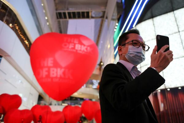 A man wearing a protective mask takes a selfie in front of hearts celebrating Valentine's Day in front of a shopping mall in Bangkok, Thailand February 13, 2020.  - Sputnik International
