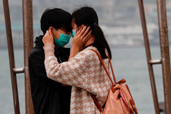 A couple wears masks as they embrace, following the outbreak of the novel coronavirus on Valentine’s Day in Hong Kong, China February 14, 2020.  - Sputnik International