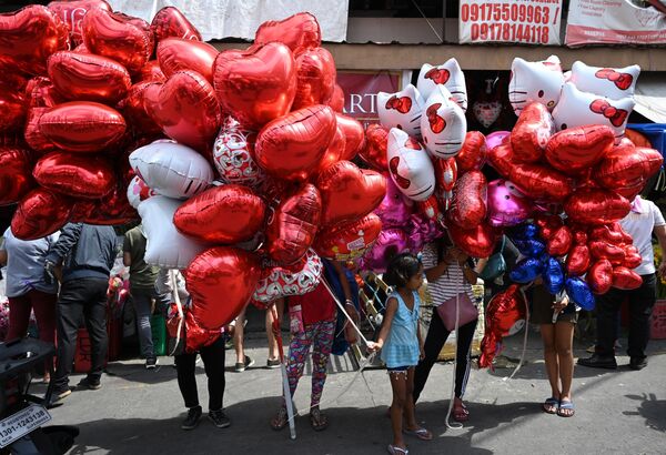 Vendors selling heart-shaped balloons wait for customers on Valentine's day at a flower market in Manila on February 14, 2020.  - Sputnik International