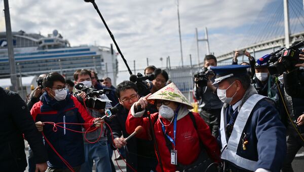  passenger (C) leaves on foot after dismembarking the Diamond Princess cruise ship in quarantine due to fears of the new COVID-19 coronavirus, at the Daikoku Pier Cruise Terminal in Yokohama on February 19, 2020 - Sputnik International