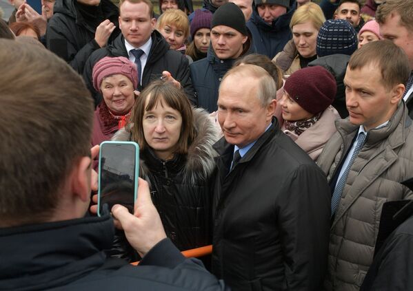 Russian President Vladimir Putin poses for pictures with citizens of Saint Petersburg after laying flowers to the city's first mayor Anatoly Sobchak's monument on 19 February - Sputnik International