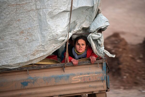 A displaced Syrian girl rides in the back of a truck on the way to Deir al-Ballut camp in Afrin's countryside along the border with Turkey, on February 19, 2020 after fleeing regime offensive on the last major rebel bastion in the country's northwest.  - Sputnik International
