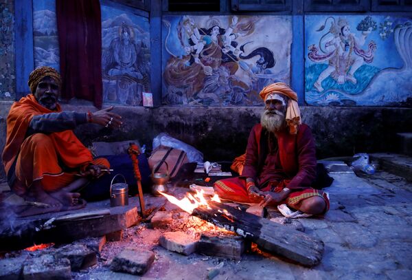 Hindu holy men, or sadhus, sit beside the fire at the premises of Pashupatinath Temple a day ahead of the Shivaratri festival in Kathmandu, Nepal February 20, 2020.  - Sputnik International