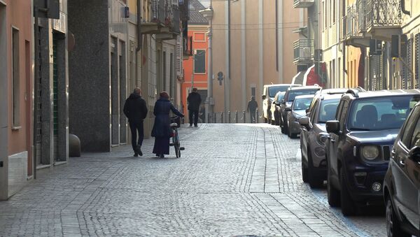 People walk down an empty street in the village of Codogno after officials told residents to stay home and suspend public activities as 14 cases of coronavirus are confirmed in northern Italy, in this still image taken from video in the province of Lodi, Italy, February 21, 2020.  - Sputnik International