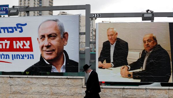 An ultra-Orthodox Jewish man walks next to Likud party election campaign banners, one depicting party leader Israeli Prime Minister Benjamin Netanyahu and the other depicting Benny Gantz, head of Blue and White party and Ahmad Tibi, co-leader of the Joint List, an Arab party, in Jerusalem February 20, 2020 - Sputnik International