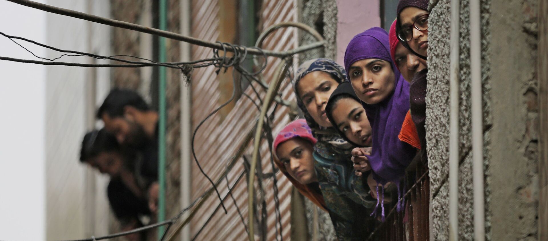 Indian Muslim women look out of a window as security officers patrol a street in New Delhi - Sputnik International, 1920, 02.09.2021