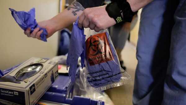 An epidemiologist holds gloves while arranging the supplies of Harborview Medical Center's home assessment team, during preparations to visit the home of a person potentially exposed to novel coronavirus at Harborview Medical Center in Seattle, Washington, U.S. February 29, 2020. REUTERS/David Ryder - Sputnik International