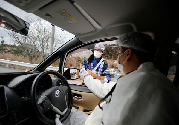 Yuji Onuma, an evacuee from Futaba Town near tsunami-crippled Fukushima Daiichi nuclear power plant, receives a security check by an official as he enters to the exclusion zone around the plant, in Futaba Town, Fukushima Prefecture, Japan February 20, 2020. Picture taken February 20, 2020. - Sputnik International