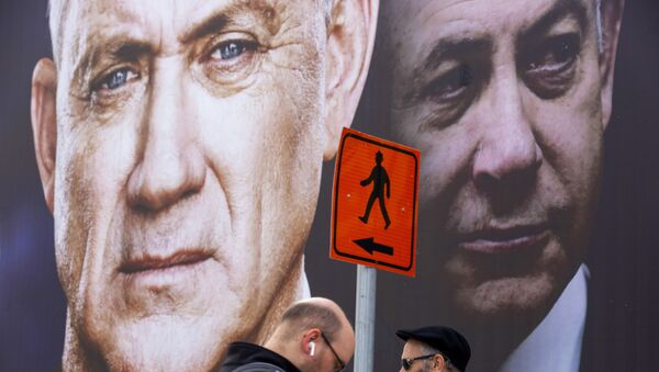 People walk past an election campaign billboard for the Blue and White party, the opposition party led by Benny Gantz, left, in Ramat Gan, Israel, Sunday, Feb. 23, 2020. Prime Minister Benjamin Netanyahu of the Likud party is pictured at right. - Sputnik International