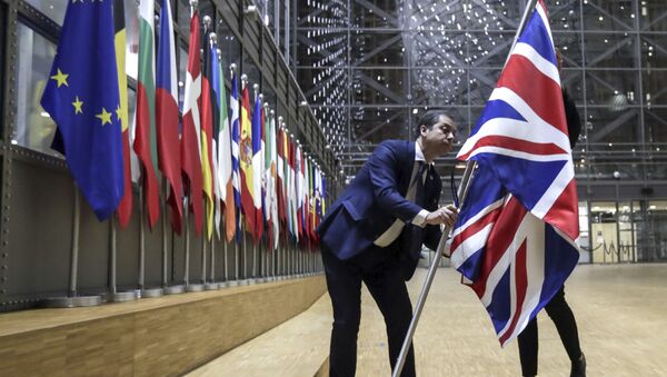 A member of protocol removes the Union flag from the atrium of the Europa building in Brussels, Friday, Jan. 31, 2020. As the United Kingdom prepared to bring to an end its 47-year EU membership, the bloc's top officials on Friday pledged to continue playing a prominent role despite the loss of a powerful affiliate - Sputnik International