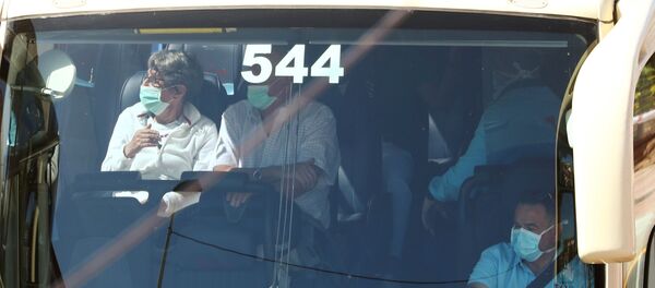 Tourists, wearing protective face masks, sit in a bus as they leave the H10 Costa Adeje Palace hotel, which is on lockdown after the novel coronavirus has been confirmed in Adeje, in the Spanish Canary Island of Tenerife, Spain, March 3, 2020 - Sputnik International
