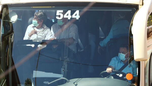 Tourists, wearing protective face masks, sit in a bus as they leave the H10 Costa Adeje Palace hotel, which is on lockdown after the novel coronavirus has been confirmed in Adeje, in the Spanish Canary Island of Tenerife, Spain, March 3, 2020 - Sputnik International
