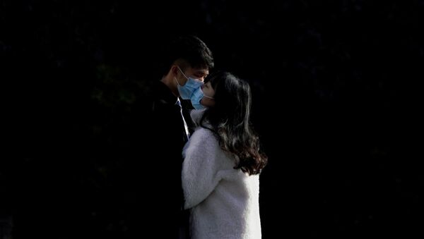 A couple wearing masks kiss at a main shopping area, in downtown Shanghai, China, as the country is hit by an outbreak of a new coronavirus, February 16, 2020 - Sputnik International