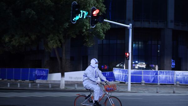 A man in a protective suit rides a shared bicycle at an intersection in Wuhan, the epicentre of the novel coronavirus outbreak, Hubei province, China March 4, 2020 - Sputnik International