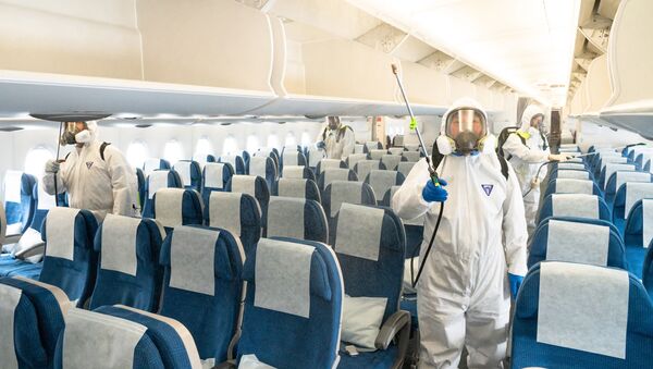 This handout photo taken on March 4, 2020 and received on March 5 from Korean Air shows workers spraying disinfectant on an airplane as part of preventive measures against the spread of the COVID-19 coronavirus, at Incheon International Airport in Incheon - Sputnik International